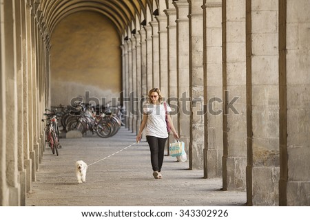 Lucca, Italy-June 6, 2015. Woman walking her dog under the arches  of building in the ancient walled city of Lucca, Italy