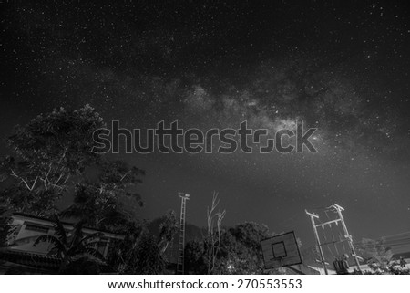Dark late night clear sky with the milky way and constellation above the outdoor basketball floor - long exposure, black and white techniques