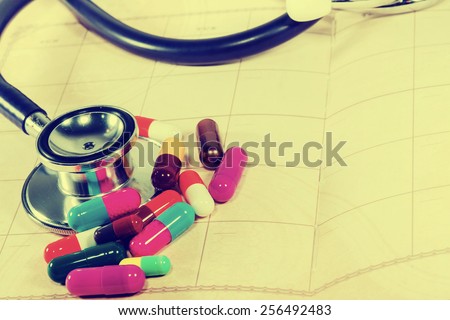Doctors Stethoscope on a blank notepad with colorful  pills for medical concept in vintage style.