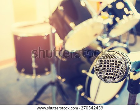 Microphone in a recording studio or concert hall with drum in out of focus background.  : Vintage style and filtered process.