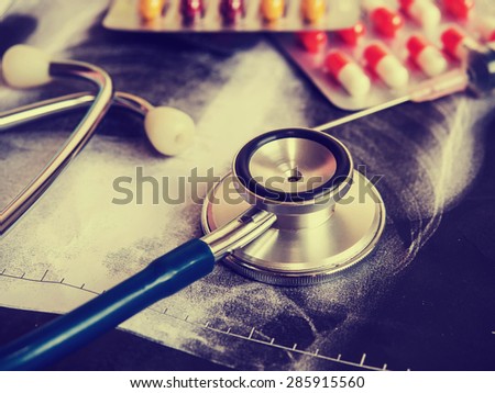 Doctors Stethoscope and capsule pills on X-ray lab document background  for medical concept in vintage style.