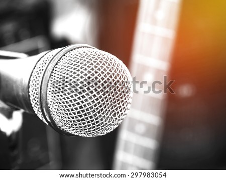 Black and white photo and lighting of the microphone in a recording studio or concert hall with electric guitar in out of focus background. : Vintage style and filtered process.