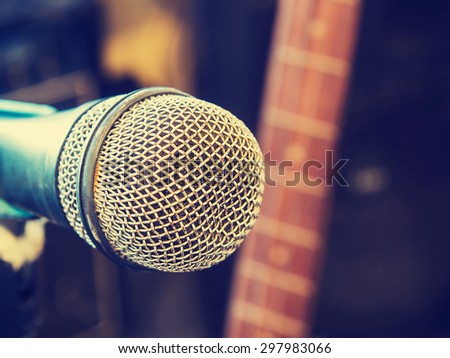 Microphone in a recording studio or concert hall with electric guitar in out of focus background. : Vintage style and filtered process.