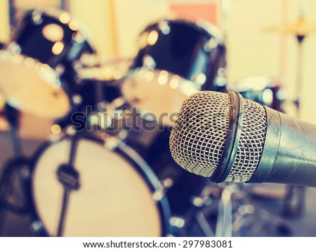 Microphone  in a recording studio or concert hall with drum in out of focus background. Vintage style and filtered process.