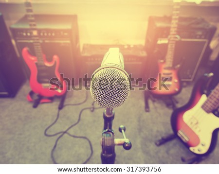 Microphone in a recording studio or concert hall with electric guitar in out of focus background. : Vintage style and filtered process.