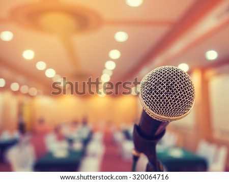 Microphone in concert hall or conference room with defocused bokeh lights in background. Extremely shallow dof. Vintage style and filtered process.