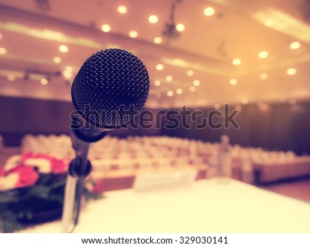 Black microphone in  empty conference room or concert hall  with defocused bokeh lights in background. Extremely shallow dof.  : Vintage style and  filtered process.