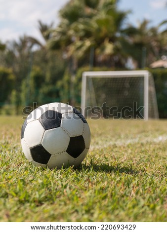 black and white soccer ball in grass on outdoor green field near five-a-side goal.
