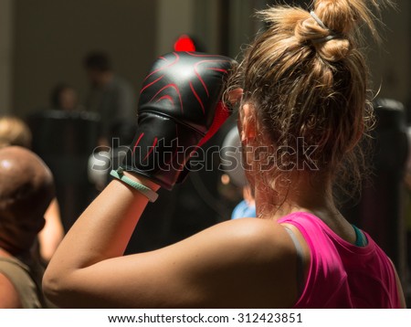 Young Woman with Boxing Glove and Pink Sportswear in Fitness Class with Punching Bag