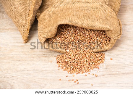 Cloth bag with buckwheat groats   on wooden background