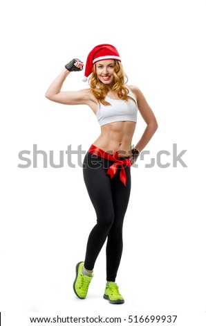 Santa hat Christmas woman tied with red bow showing biceps. Winner energy from young sexy red curly fitness model isolated on white background.