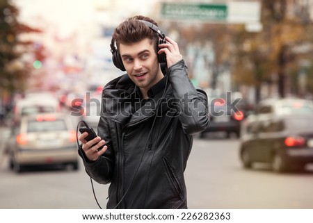 man in headphones on the street. Standing with phone in hand