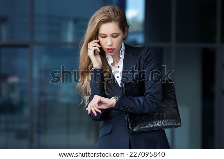 business woman speaks by phone and looks at her watch