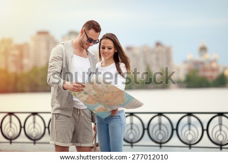 young couple with map in hand on the background of the city