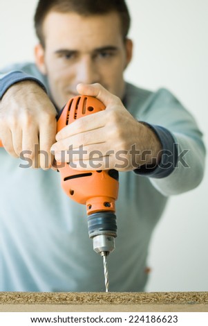 Man using drill, focus on drill in foreground
