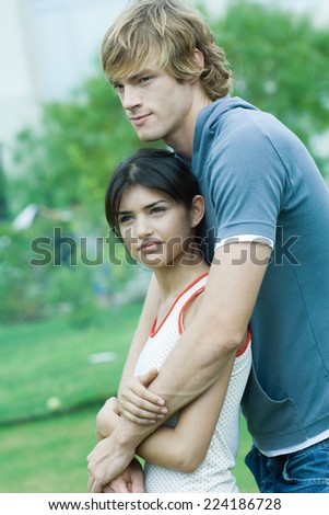 Young couple, man with arms around woman, woman leaning against him