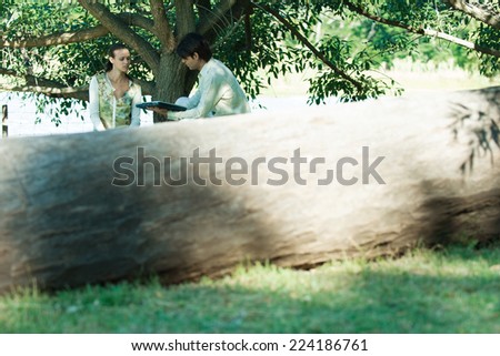 Couple with laptop, tree trunk in foreground