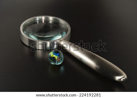 Glass marble and magnifying glass, close-up