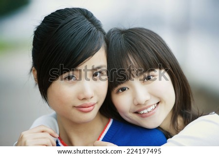 Two female friends, one with arms around the other\'s shoulders
