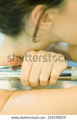 Woman holding onto metal bar, close-up of hand and neck