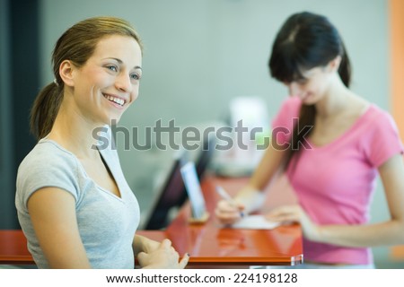 Young women signing in at counter of health club