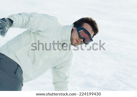 Young man bending over in snow, dressed in ski clothing, waist up
