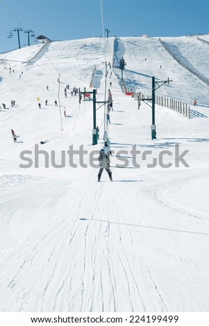 Young skiers using ski lift in the distance, rear view