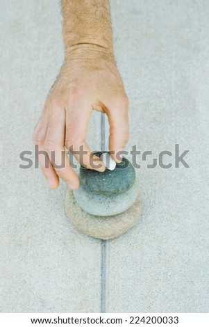Man stacking pebbles, cropped view of hand