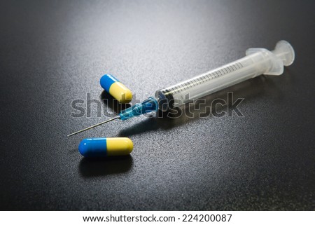 Syringe and drug capsules, close-up