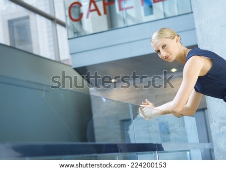 Businesswoman, leaning arms on rail, looking at camera