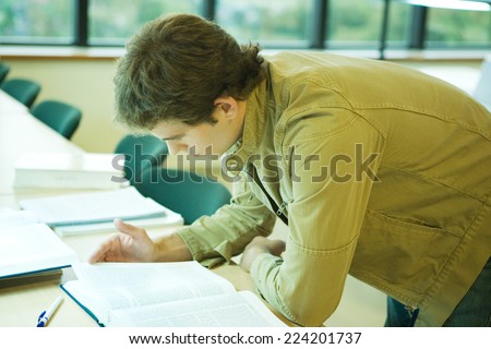 Male college student leaning forward on table, studying