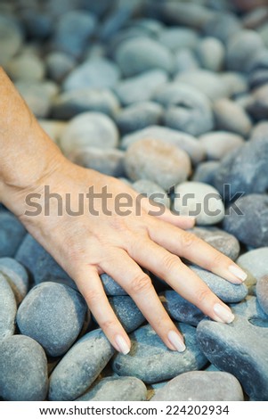 Woman touching pebbles, cropped view of hand