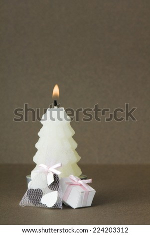 White Christmas tree shaped candle with miniature gifts set at base