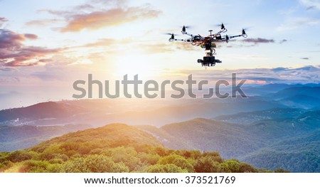 The drone with the professional camera takes pictures of the misty mountains at sunset