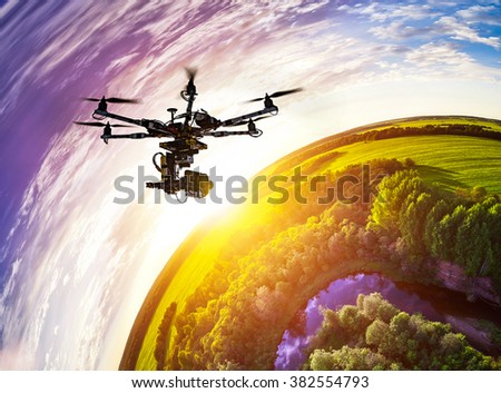 Drone with professional cinema camera flying over a blue calm river in the forests and fields at the sunset. Little planet effect.