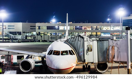 Airplane parked at the airport and preparation for next flight. Loading cargo on the plane in airport terminal at night. Workers cargo service airport.