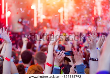 Audience with hands in the air at the festival. Fun concert party disco with blurred light background. Hands  in the crowd at a music festival. Night entertainment, music, happy, party