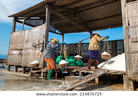 NhaTrang, Vietnam. Women collect salt in salt farm in traditional industry practice.