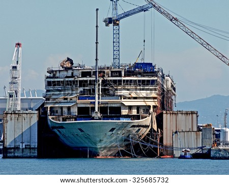 GENOA, ITALY - OCTOBER 7, 2015: The wreck of the Costa Concordia loses the bridges during the demolition. Workers and cranes working on the hull.