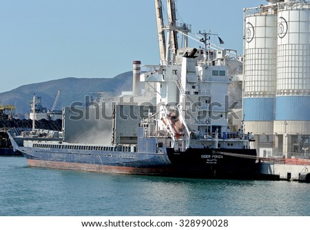 GENOA, ITALY - SEPTEMBER 24, 2015: Cleaning of the holds of a cargo ship with cement dust in the air. In the picture the Cargo Ship SIDER PONZA.