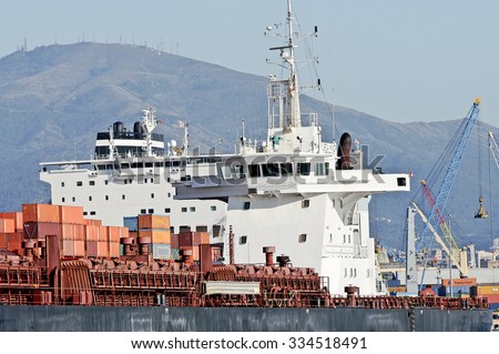 GENOA, ITALY - OCTOBER 31, 2015: The cargo ships Jolly Cobalto e Ursa Minor in the commercial port of Genoa. In the background the high cranes and the lighthouse symbol of the city.