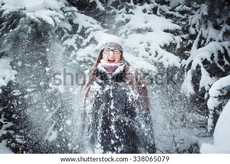 Winter girl and snow fir tree. Beautiful young woman having a fun in the snow