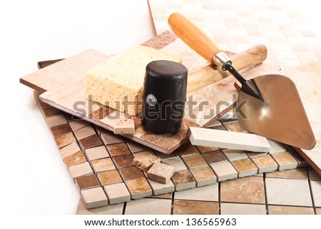 Ceramic and marble tile, trowel, a sponge and a rubber mallet on white background