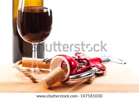 A glass of red wine, bottle opener with a cork from a bottle on a white background