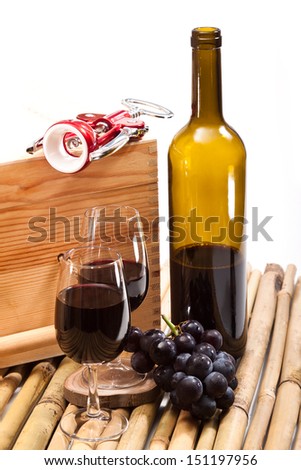 Red wine by the glass for wine and a bunch of ripe grapes, a bottle of wine on bamboo rods