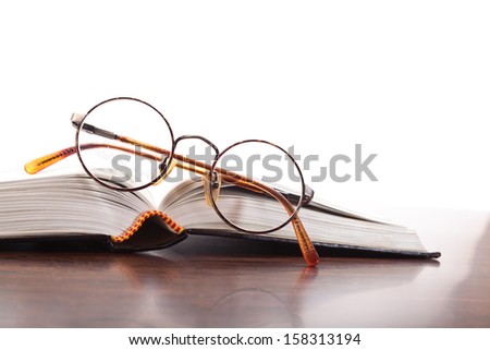 Open book and glasses with circular rim on a white background