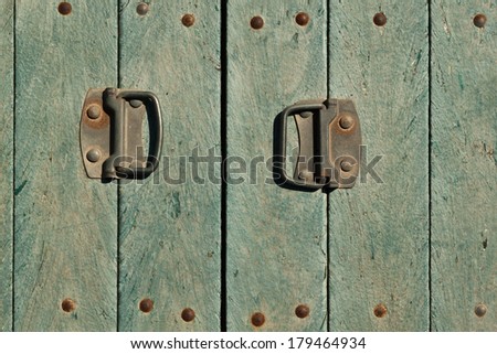 Old doors with the sun scorched paint and two handles covered with rust