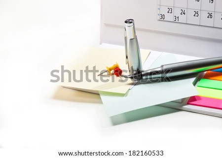 Desk calendar, pen, pieces of paper on white background
