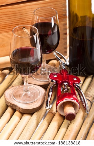 Two glasses of red wine and opener with cork from the bottle