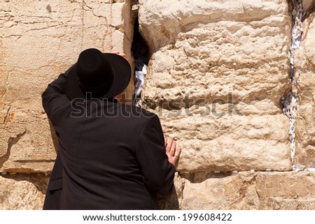 Man in religious dress prays at the Wailing Wall